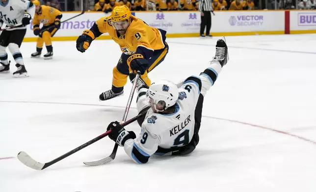 Utah Hockey Club center Clayton Keller, bottom, slides as he chases the puck with Nashville Predators left wing Filip Forsberg, top, during the third period of an NHL hockey game Saturday, Nov. 9, 2024, in Nashville, Tenn. (AP Photo/Mark Humphrey)