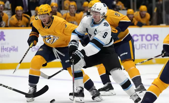 Nashville Predators defenseman Jeremy Lauzon, left, and Utah Hockey Club center Clayton Keller (9) chase the puck during the first period of an NHL hockey game Saturday, Nov. 9, 2024, in Nashville, Tenn. (AP Photo/Mark Humphrey)