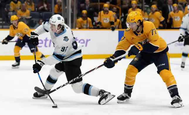 Nashville Predators right wing Luke Evangelista (77) tries to block Utah Hockey Club center Logan Cooley (92) as Cooley takes a shot during the third period of an NHL hockey game Saturday, Nov. 9, 2024, in Nashville, Tenn. (AP Photo/Mark Humphrey)