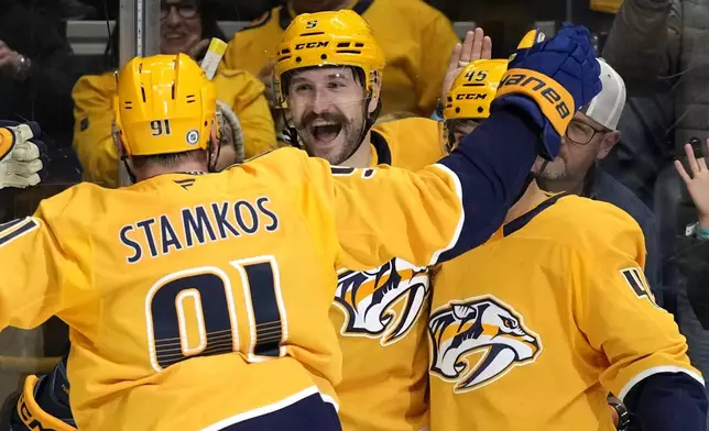 Nashville Predators left wing Filip Forsberg, center, celebrates his second goal of the game with Steven Stamkos (91) during the second period of an NHL hockey game against the Utah Hockey Club Saturday, Nov. 9, 2024, in Nashville, Tenn. (AP Photo/Mark Humphrey)