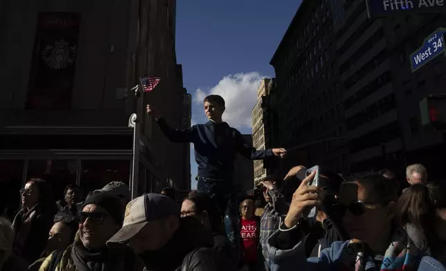 A boy waves an American flag as crowds watch the annual Veterans Day Parade, Monday, Nov. 11, 2024, in New York. (AP Photo/Adam Gray)