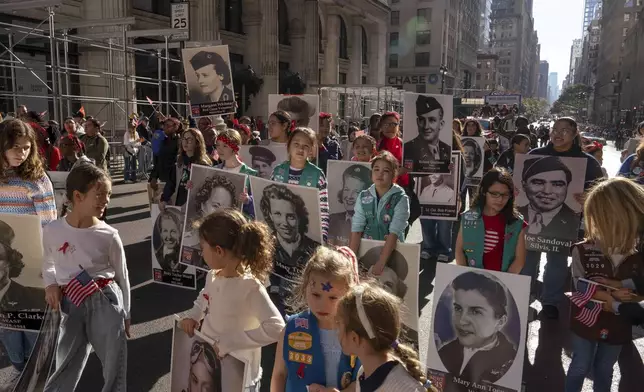 Girl Scouts carry photographs of people who served in World War II during the annual Veterans Day Parade, Monday, Nov. 11, 2024 in New York. (AP Photo/Adam Gray)