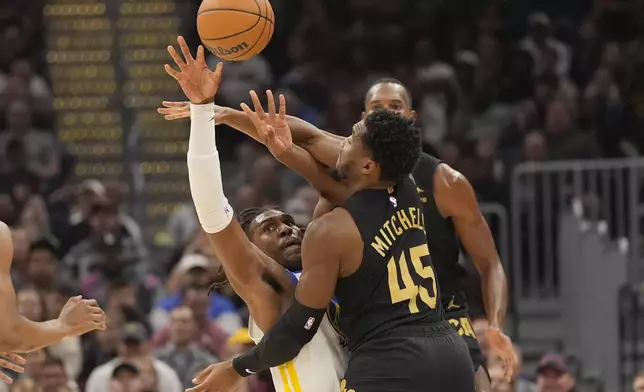 Golden State Warriors forward Kevon Looney, left, and Cleveland Cavaliers guard Donovan Mitchell (45) reach for the ball in the first,half of an NBA basketball game, Friday, Nov. 8, 2024, in Cleveland. (AP Photo/Sue Ogrocki)