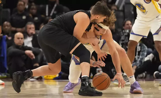 Cleveland Cavaliers guard Ty Jerome, left, and Golden State Warriors guard Brandin Podziemski, right, reach for the ball in the first half of an NBA basketball game, Friday, Nov. 8, 2024, in Cleveland. (AP Photo/Sue Ogrocki)