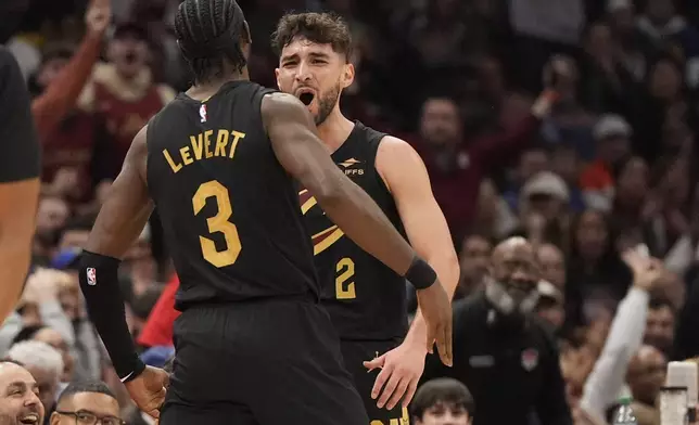 Cleveland Cavaliers guard Ty Jerome, right, celebrates a three-point basket with teammate Caris LeVert (3) in the first half of an NBA basketball game against the Golden State Warriors, Friday, Nov. 8, 2024, in Cleveland. (AP Photo/Sue Ogrocki)
