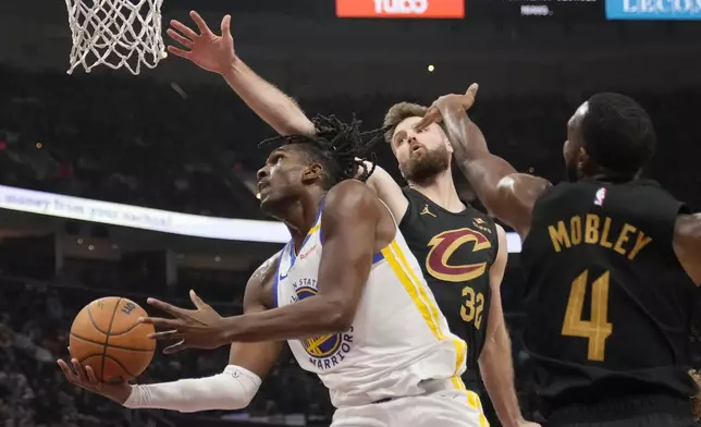 Golden State Warriors forward Kevon Looney, left, goes to the basket in front of Cleveland Cavaliers forward Dean Wade (32) and forward Evan Mobley (4) in the first half of an NBA basketball game, Friday, Nov. 8, 2024, in Cleveland. (AP Photo/Sue Ogrocki)