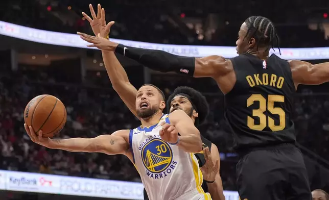 Golden State Warriors guard Stephen Curry (30) goes to the basket in front of Cleveland Cavaliers center Jarrett Allen, rear, and forward Isaac Okoro (35) in the first half of an NBA basketball game, Friday, Nov. 8, 2024, in Cleveland. (AP Photo/Sue Ogrocki)