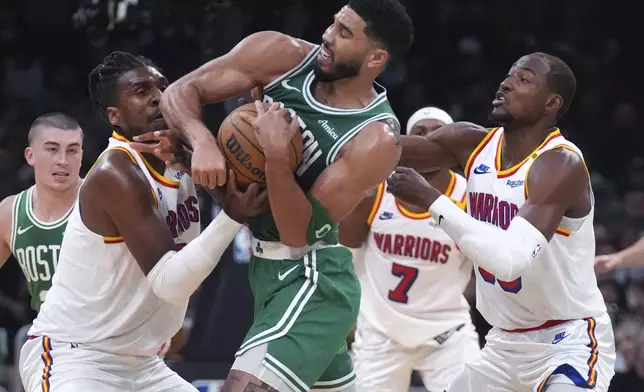 Boston Celtics forward Jayson Tatum, center battles for the ball against Golden State Warriors forward Kevon Looney, left, during the first half of an NBA basketball game, Wednesday, Nov. 6, 2024, in Boston. At right is Golden State Warriors forward Jonathan Kuminga. (AP Photo/Charles Krupa)