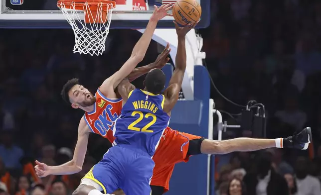 Oklahoma City Thunder forward Chet Holmgren, left, and Golden State Warriors forward Andrew Wiggins (22) collide as Wiggins shoots during the first half of an NBA basketball game Sunday, Nov. 10, 2024, in Oklahoma City. Holmgren was injured on the play and helped off the court. (AP Photo/Nate Billings)