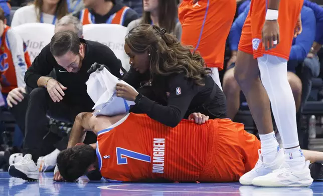 Oklahoma City Thunder staff help Thunder forward Chet Holmgren (7) after he was injured during the first half of an NBA basketball game against the Golden State Warriors, Sunday, Nov. 10, 2024, in Oklahoma City. (AP Photo/Nate Billings)