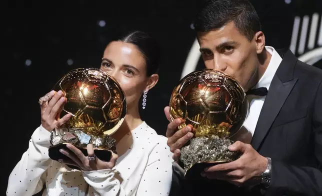 Barcelona's Spanish player Aitana Bonmati, left, and Manchester City's Spanish player Rodri kiss their 2024 Ballon d'Or trophies during the 68th Ballon d'Or (Golden Ball) award ceremony at Theatre du Chatelet in Paris, Monday, Oct. 28, 2024. (AP Photo/Michel Euler)