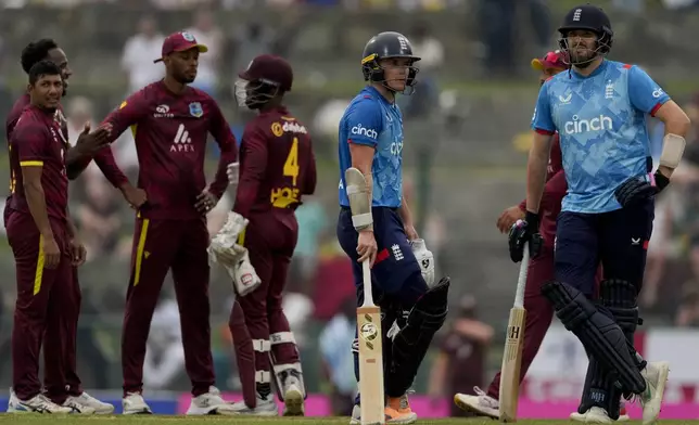 England's Jamie Overton, right, and Sam Curran look at the scoreboard during the first ODI cricket match against West Indies at Sir Vivian Richards Ground in North Sound, Antigua and Barbuda, Thursday, Oct. 31, 2024. (AP Photo/Ricardo Mazalan)