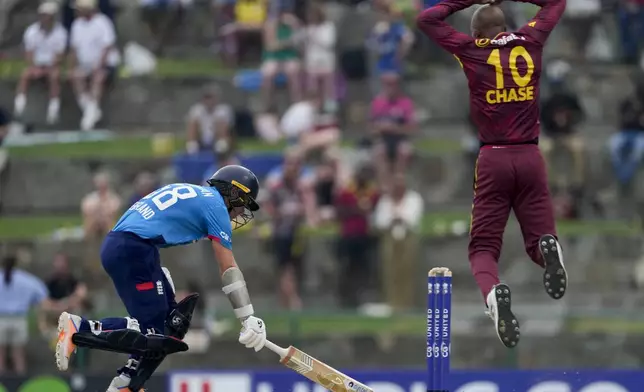 England's Sam Curran safely makes his ground as West Indies' bowler Roston Chase jumps during the first ODI cricket match at Sir Vivian Richards Ground in North Sound, Antigua and Barbuda, Thursday, Oct. 31, 2024. (AP Photo/Ricardo Mazalan)