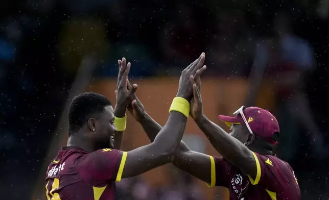 West Indies' bowler Romario Shepherd, left, celebrates the dismissal of England's captain Liam Livingstone with teammate Sherfane Rutherford during the third ODI cricket match at Kensington Oval in Bridgetown, Barbados, Wednesday, Nov. 6, 2024. (AP Photo/Ricardo Mazalan)