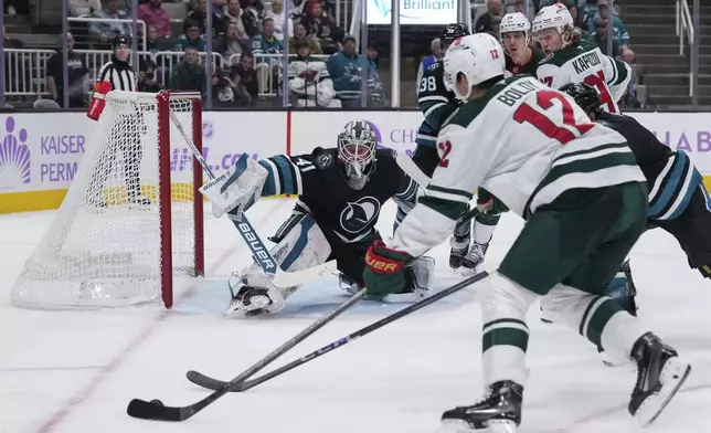 San Jose Sharks goaltender Vitek Vanecek, center, watches as Minnesota Wild left wing Matt Boldy (12) moves the puck during the second period of an NHL hockey game Thursday, Nov. 7, 2024, in San Jose, Calif. (AP Photo/Godofredo A. Vásquez)