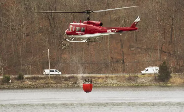 This image provided by New Jersey Department of Environmental Protection shows a New Jersey Forest Fire Service helicopter getting water for the wildfire in Jennings Creek, N.J., Saturday, Nov. 9, 2024. (New Jersey Department of Environmental Protection via AP)