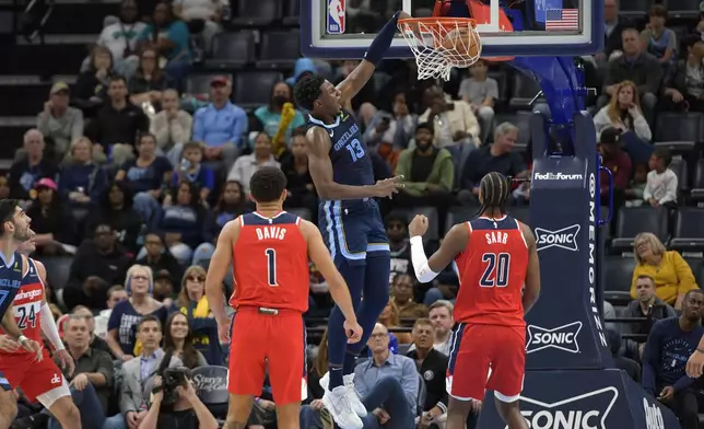 Memphis Grizzlies forward Jaren Jackson Jr. (13) dunks past Washington Wizards guard Johnny Davis (1) and forward Alex Sarr (20) in the first half of an NBA basketball game Friday, Nov. 8, 2024, in Memphis, Tenn. (AP Photo/Brandon Dill)