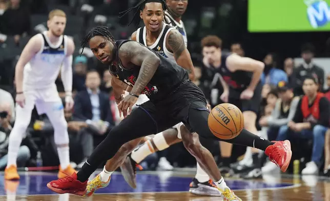 Toronto Raptors' Davion Mitchell (front) and Minnesota Timberwolves' Rob Dillingham (back) battle for the loose ball during first half NBA basketball action in Toronto on Thursday, Nov. 21, 2024. (Frank Gunn/The Canadian Press via AP)