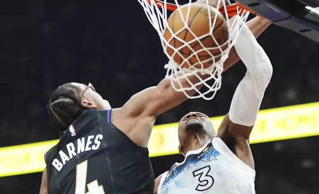 Minnesota Timberwolves' Jaden McDaniels (3) dunks as Toronto Raptors' Scottie Barnes (4) defends during first half NBA basketball action in Toronto on Thursday, Nov. 21, 2024. (Frank Gunn/The Canadian Press via AP)