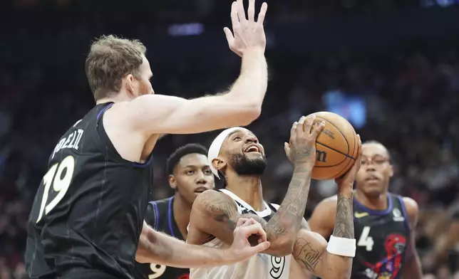 Minnesota Timberwolves' Nickeil Alexander-Walker (9) drives as Toronto Raptors' Jakob Poeltl (19) defends during first-half NBA basketball game action in Toronto, Thursday, Nov. 21, 2024. (Frank Gunn/The Canadian Press via AP)