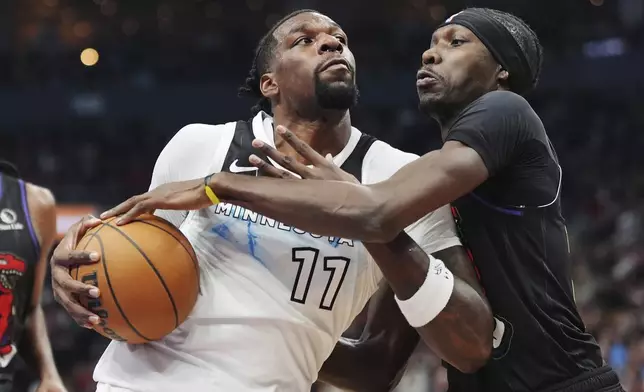 Minnesota Timberwolves' Naz Reid (11) is stopped by Toronto Raptors' Chris Boucher (right) during first half NBA basketball action in Toronto on Thursday, Nov. 21, 2024. (Frank Gunn/The Canadian Press via AP)