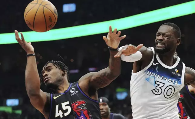 Toronto Raptors' Davion Mitchell (45) and Minnesota Timberwolves' Julius Randle (30) battle for a rebound during first-half NBA basketball game action in Toronto, Thursday, Nov. 21, 2024. (Frank Gunn/The Canadian Press via AP)