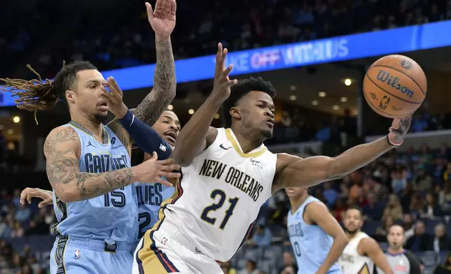 New Orleans Pelicans center Yves Missi (21) handles the ball ahead of Memphis Grizzlies forward Brandon Clarke (15) and guard Ja Morant in the first half of an Emirates NBA Cup basketball game Friday, Nov. 29, 2024, in Memphis, Tenn. (AP Photo/Brandon Dill)