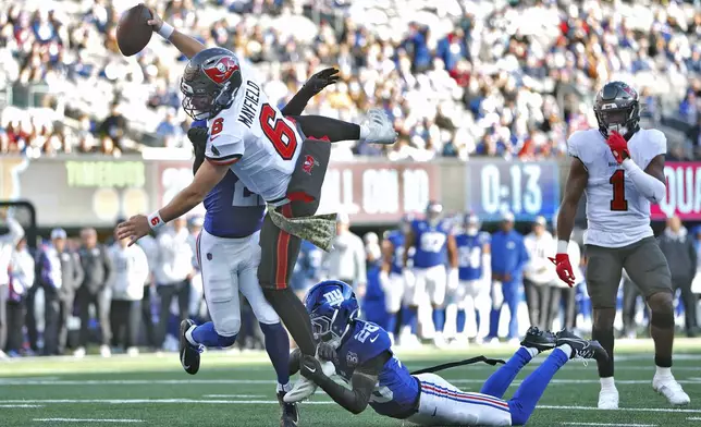 Tampa Bay Buccaneers quarterback Baker Mayfield (6) scores past New York Giants cornerback Dru Phillips (22) and cornerback Cor'Dale Flott (28) during the first half of an NFL football game Sunday, Nov. 24, 2024, in East Rutherford, N.J. (AP Photo/Rich Schultz)