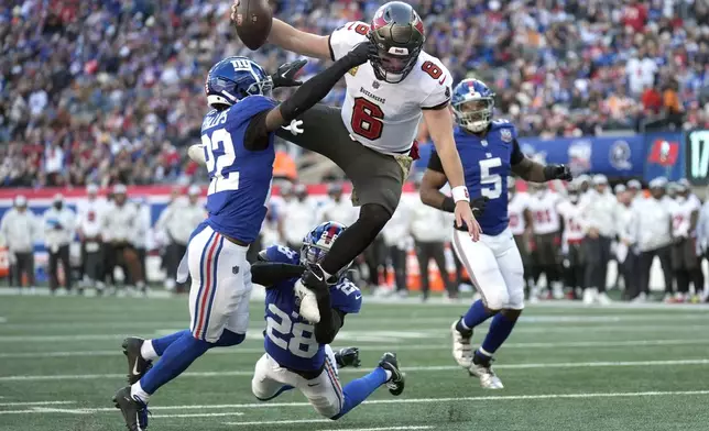 Tampa Bay Buccaneers quarterback Baker Mayfield (6) scores past New York Giants cornerback Dru Phillips (22), cornerback Cor'Dale Flott (28) and linebacker Kayvon Thibodeaux (5) during the first half of an NFL football game Sunday, Nov. 24, 2024, in East Rutherford, N.J. (AP Photo/Seth Wenig)