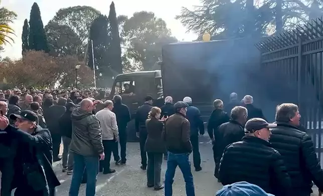 In this photo taken from video released by the Information Center of the President of the Republic of Abkhazia, a Protesters' truck breaks through the closed gate in the fence outside the parliament building of the Georgian separatist region of Abkhazia as tensions flared over a proposed pact that would allow Russians to buy apartments in the region, Georgia, on Friday, Nov. 15, 2024, (Information Center of the President of the Republic of Abkhazia via AP)