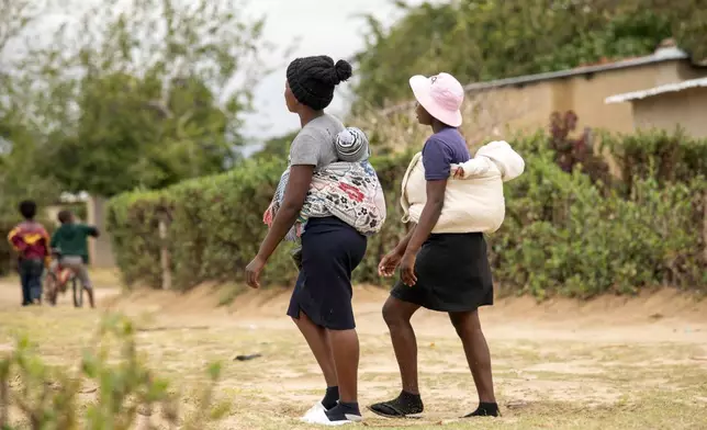 19 year old Sithulisiwe Moyo, right, and a friend, carry their babies on their backs at an outtreach clinic in Epworth, Zimbabwe, Thursday, Nov. 14, 2024. (AP Photo/Aaron Ufumeli)