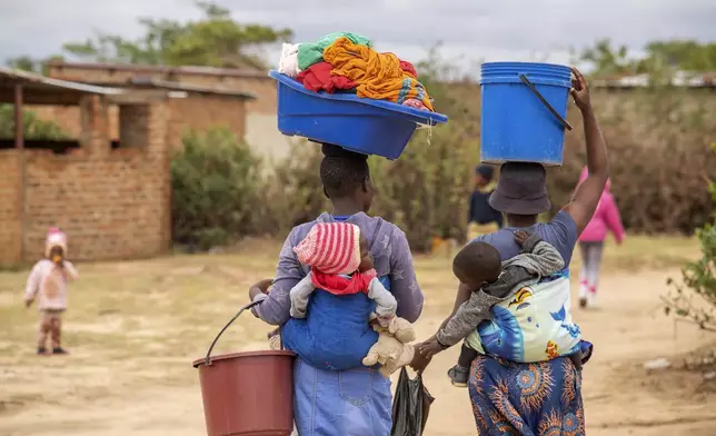 Women, with children on their backs carry out chores in Epworth, Zimbabwe, Thursday, Nov. 14, 2024. (AP Photo/Aaron Ufumeli)