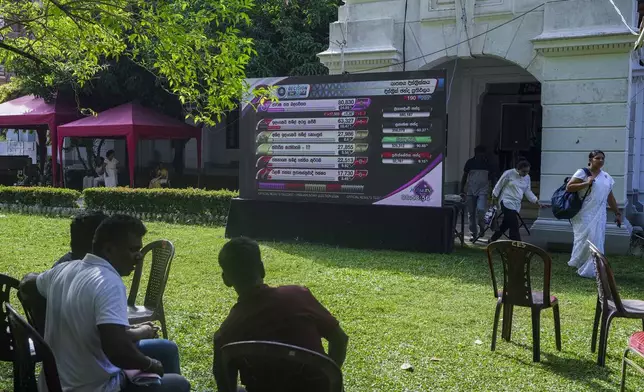 People watch polling results displayed on a giant screen outside a vote counting center following the parliamentary election in Colombo, Sri Lanka, Friday, Nov. 15, 2024. (AP Photo/Eranga Jayawardena)