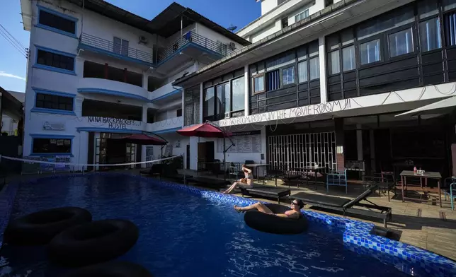 Foreign tourists relax at a swimming pool at Nana Backpack hostel in Vang Vieng, Laos, Tuesday, Nov. 19, 2024. (AP Photo/Anupam Nath)