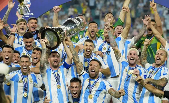 FILE - Argentina's Lionel Messi, holding the Copa America trophy, celebrates with teammates their victory over Colombia in the Copa America final soccer match in Miami Gardens, Fla., July 15, 2024. (AP Photo/Rebecca Blackwell, File)