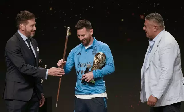 FILE - CONMEBOL President Alejandro Dominguez present to soccer legend Lionel Messi the Leadership and Command of World Soccer baton as Claudio Tapia, president of the Argentina Soccer Association or AFA, looks on during a ceremony at CONMEBOL headquarters in Asuncion, Paraguay, March 27, 2023. (AP Photo/Jorge Saenz, File)