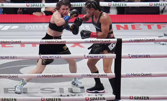 Amanda Serrano, right, hits Katie Taylor during their undisputed super lightweight title bout, Friday, Nov. 15, 2024, in Arlington, Texas. (AP Photo/Julio Cortez)