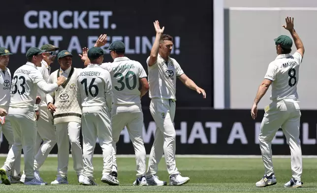 Australia's Mitchell Marsh, right, walks up to teammate Josh Hazlewood to celebrate the wicket of India's Virat Kohli during play in the first cricket test between India and Australia in Perth, Australia, Friday, Nov. 22, 2024. (AP Photo/Trevor Collens)