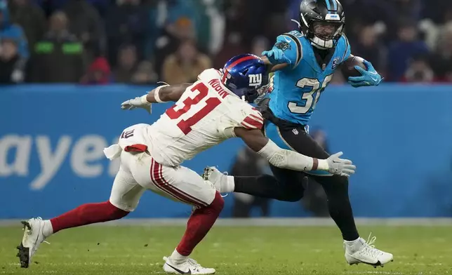 Carolina Panthers running back Chuba Hubbard run past ffNew York Giants safety Tyler Nubin during the second half of an NFL football game, Sunday, Nov. 10, 2024, in Munich, Germany. (AP Photo/Matthias Schrader)