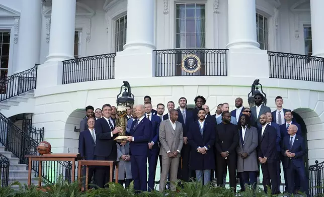 Boston Celtics owner Wyc Grousbeck, from left, and President Joe Biden hold up the Boston Celtics' trophy as they pose for a team photo to celebrate the Celtics victory in the 2024 National Basketball Association Championship during an event on the South Lawn of the White House in Washington, Thursday, Nov. 21, 2024. (AP Photo/Susan Walsh)