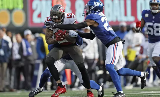 Tampa Bay Buccaneers wide receiver Mike Evans (13) is stopped by New York Giants safety Jason Pinnock (27) after a catch during the first half of an NFL football game Sunday, Nov. 24, 2024, in East Rutherford, N.J. (AP Photo/Rich Schultz)