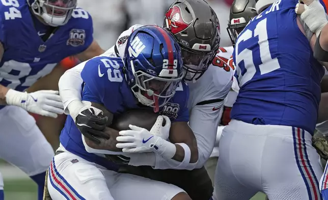 New York Giants running back Tyrone Tracy Jr. (29) is stopped by Tampa Bay Buccaneers linebacker Joe Tryon-Shoyinka (9) on a run during the first half of an NFL football game Sunday, Nov. 24, 2024, in East Rutherford, N.J. (AP Photo/Seth Wenig)