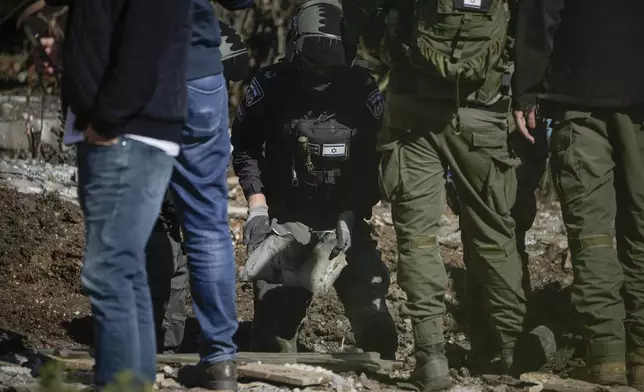 Police bomb squad officers collect the pieces of a rocket fired from Lebanon that landed in a backyard in Kiryat Shmona, northern Israel, Tuesday Nov. 26, 2024. (AP Photo/Leo Correa)