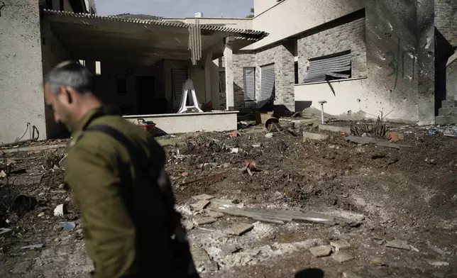 An Israeli soldier inspects the site where a rocket fired from Lebanon landed in a backyard in Kiryat Shmona, northern Israel, Tuesday Nov. 26, 2024. (AP Photo/Leo Correa)