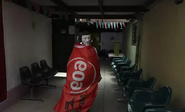 A voter wrapped in a flag of the Frente Amplio (Broad Front) arrives to a polling station to vote in the presidential run-off in Montevideo, Uruguay, Sunday, Nov. 24, 2024. (AP Photo/Matilde Campodonico)