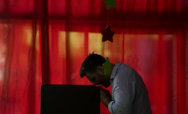 A voter chooses his preference at polling station in the presidential run-off election in Montevideo, Uruguay, Sunday, Nov. 24, 2024. (AP Photo/Natacha Pisarenko)