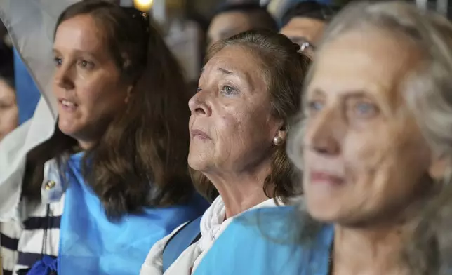 Supporters of Alvaro Delgado, presidential candidate for the ruling National Party, listen to early results from pollsters at the party's campaign night headquarters in Montevideo, Uruguay, after polls closed in the presidential run-off election, Sunday, Nov. 24, 2024. (AP Photo/Matilde Campodonico)