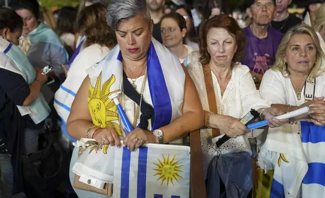 Supporters of Alvaro Delgado, presidential candidate for the ruling National Party, listen to early results from pollsters at the party's campaign night headquarters in Montevideo, Uruguay, after polls closed in the presidential run-off election, Sunday, Nov. 24, 2024. (AP Photo/Matilde Campodonico)