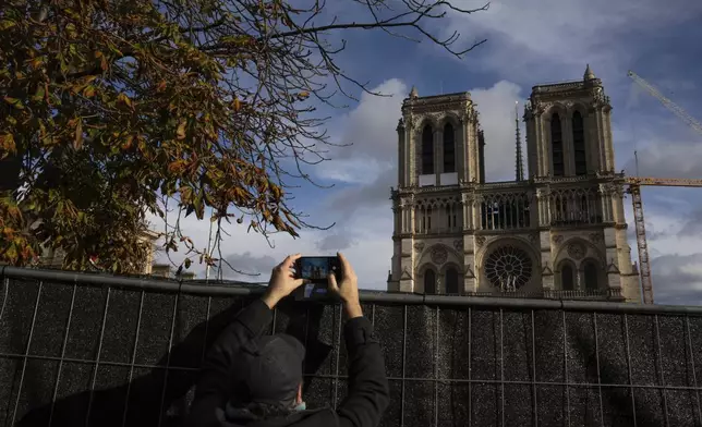 A visitor takes photographs of Notre-Dame cathedral in Paris, Wednesday, Nov. 20, 2024. (AP Photo/Louise Delmotte)