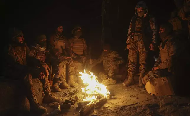 Syrian opposition fighters warm themselves by a fire in the streets of Aleppo, late Friday Nov. 29, 2024. (AP Photo/Ghaith Alsayed)